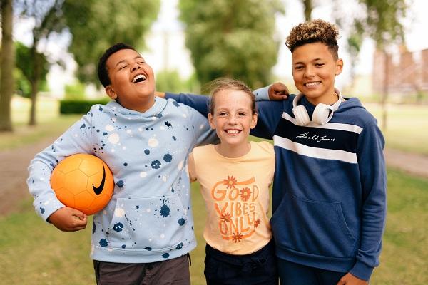Three children smiling and one holding a football